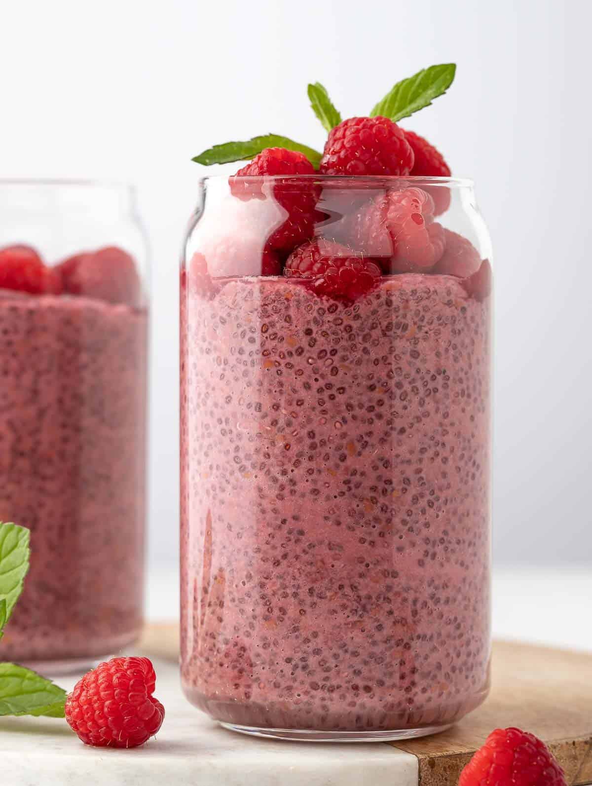 close up shot of Raspberry Protein Chia Seed Pudding, topped with fresh raspberry and mint leaf on top.