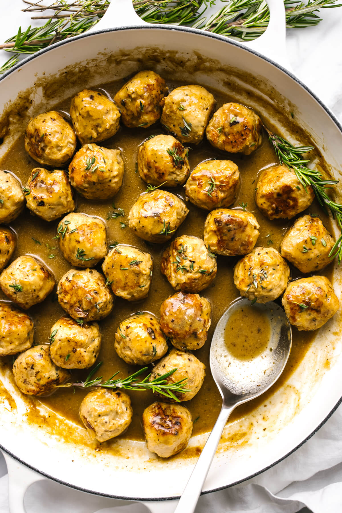 Turkey meatballs in a pan with maple mustard sauce with a spoon.