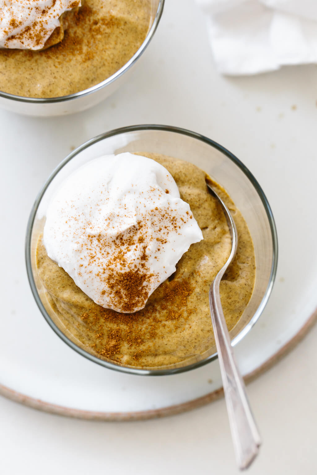 Pumpkin chia pudding in a glass jar with a dollop of whipped cream and cinnamon.
