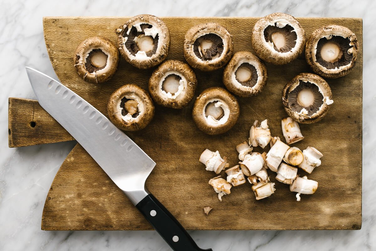 Prepping mushrooms on a wooden board for stuffed mushrooms.